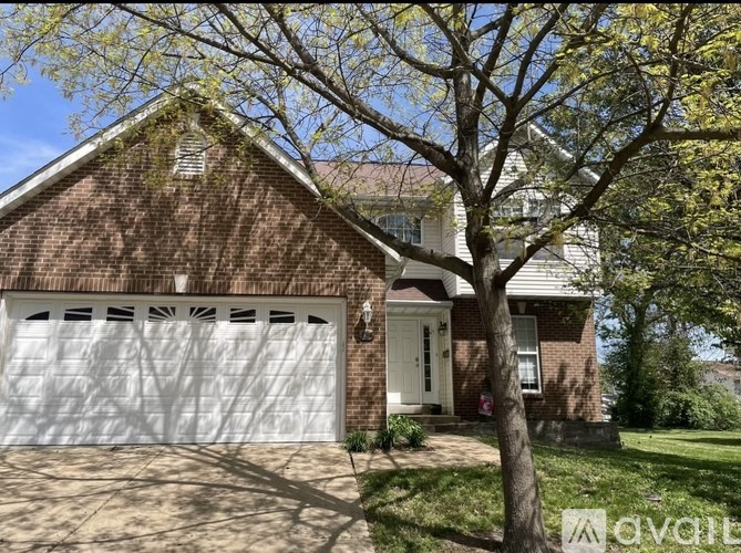 A house with a white garage door and a tree in front.