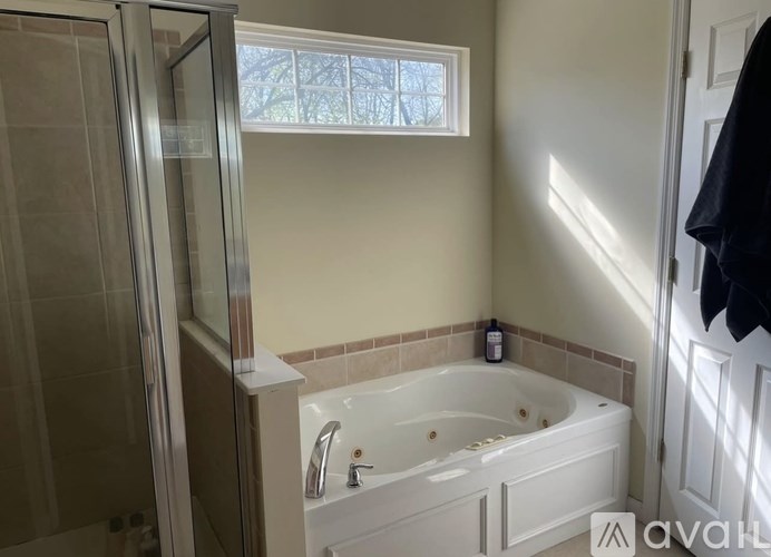 A bathroom with a tub, shower, and a window.