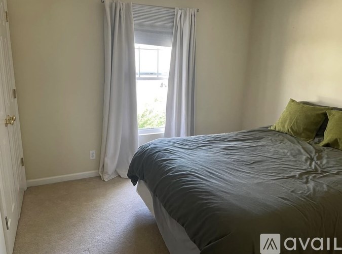 A bedroom with a large bed and a window with curtains.