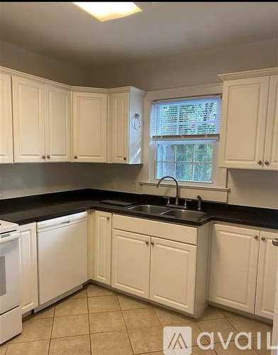 A kitchen with white cabinets and a black countertop.
