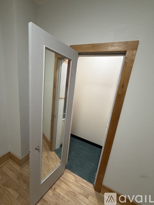A white door with a mirror on the left side and a wooden frame.