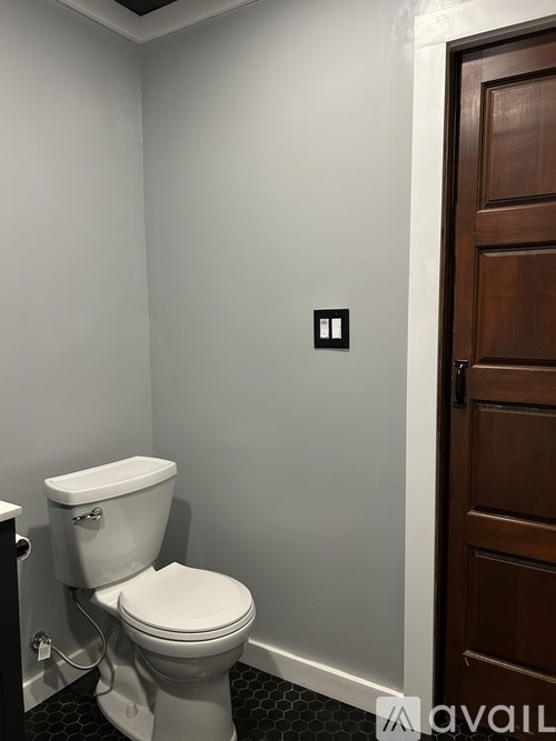 A white toilet in a bathroom with a wooden door.