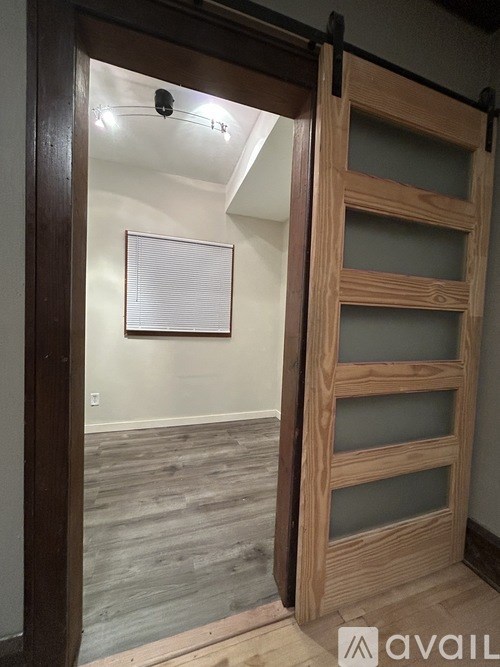 A wooden door is open to a room with a whiteboard on the wall.