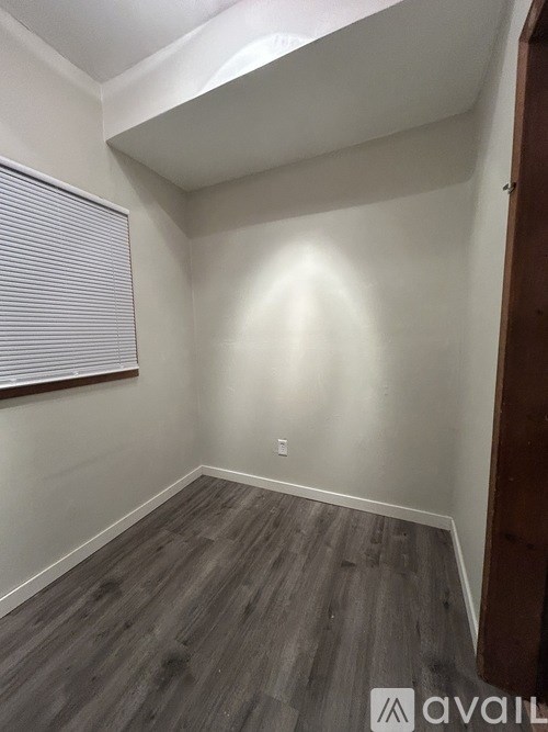 A room with wooden flooring and a window with blinds.