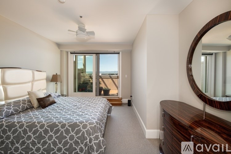 A bedroom with a large bed and a view of the outside through the window.