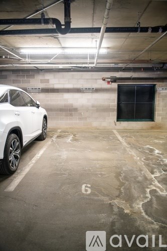 A white car is parked in a garage with the number 6 on the ground.