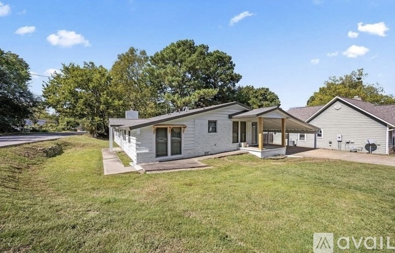 A house with a white exterior and a grey roof is surrounded by a grassy lawn.