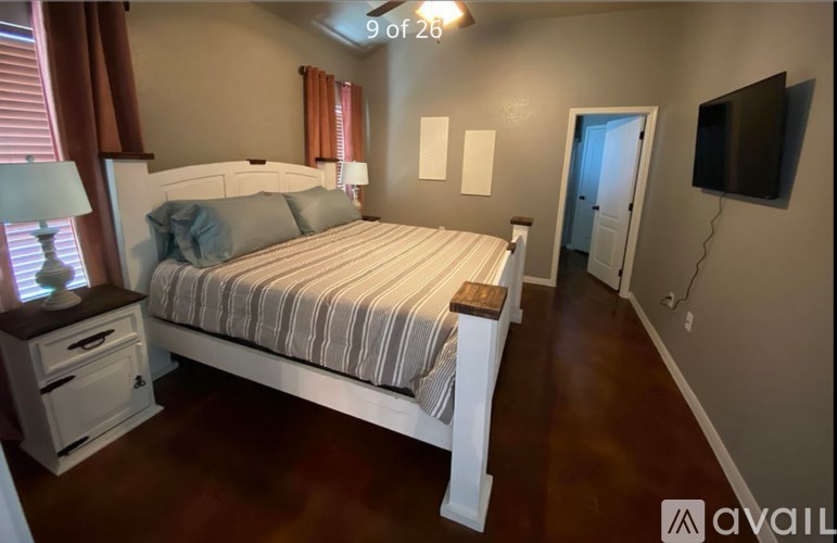 A bedroom with a large bed and a television on the wall.