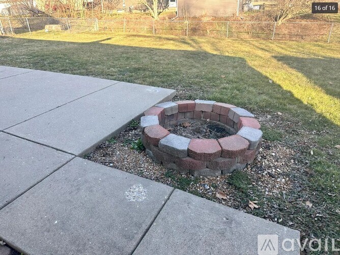 A brick fire pit sits in the middle of a grassy area.