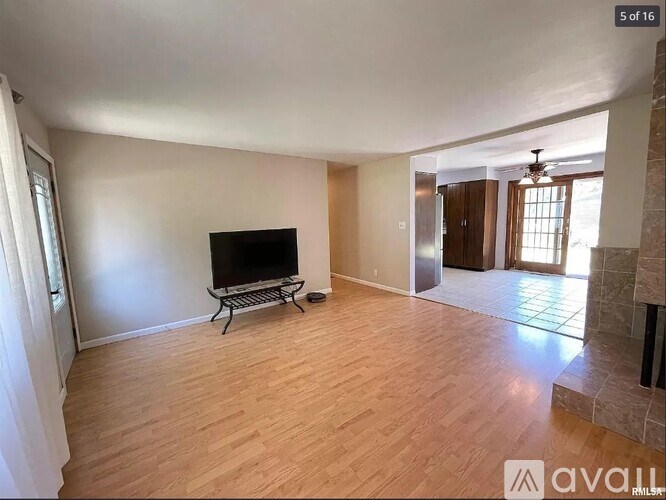 A living room with a flat screen TV and wooden flooring.