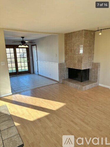 A living room with a fireplace and a ceiling fan.