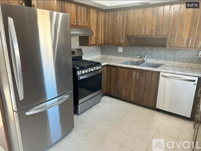 A kitchen with a stainless steel refrigerator, black oven, and white dishwasher.
