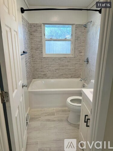 A bathroom with a toilet, tub, and window.