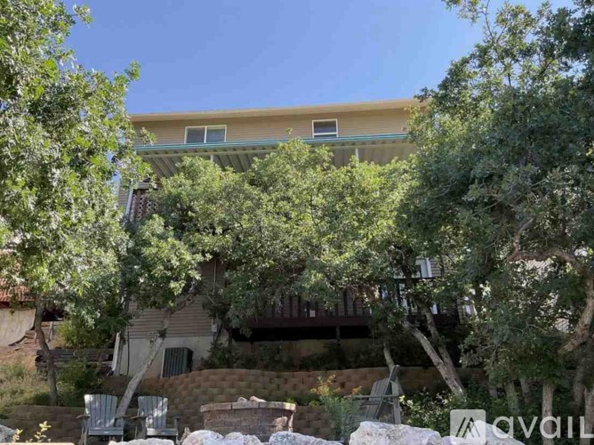A house with a balcony surrounded by trees.