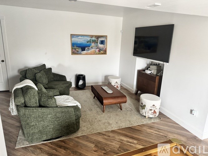 A living room with a couch, a coffee table, a TV, and a painting on the wall.