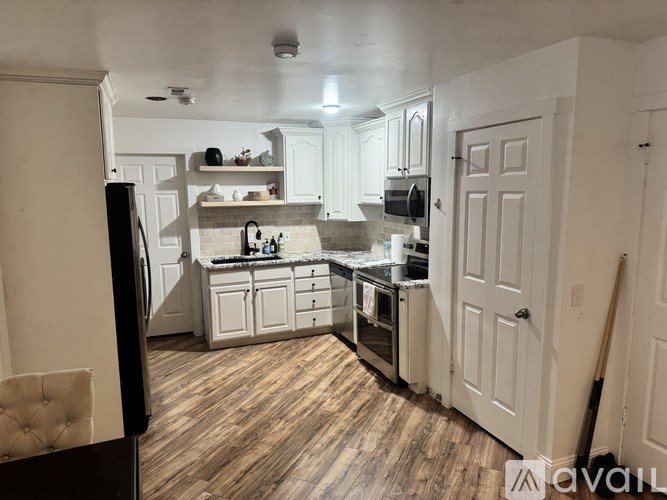 A kitchen with white cabinets and a wooden floor.