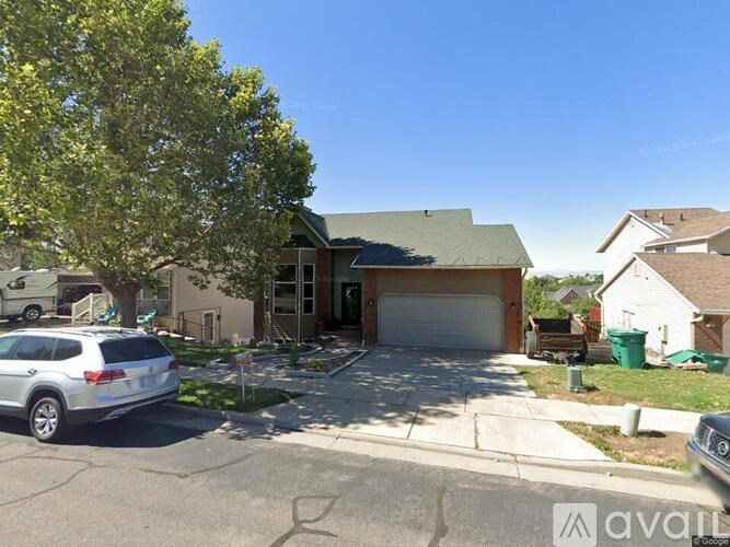 A silver SUV is parked in front of a house with a tree to the left.