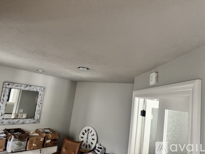 A room with a mirror, a clock, and boxes on the table.