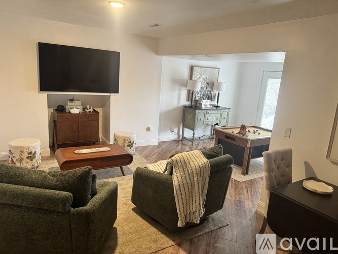 A living room with a green couch and a television mounted on the wall.