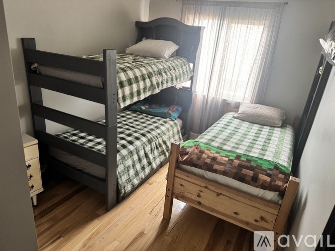 A bedroom with two beds, one with a green and white checkered bedspread.