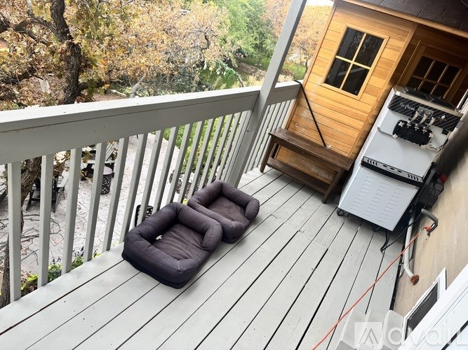 A small wooden cabin with a grey sofa on a wooden deck.