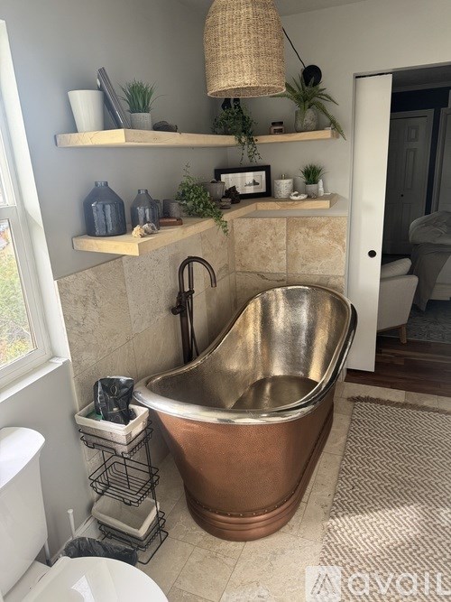 A bathroom with a copper bathtub and a white toilet.