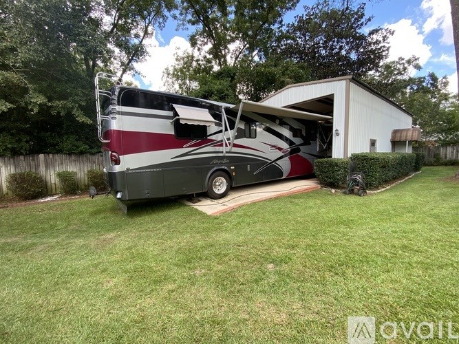 A red and white RV is parked in a yard.