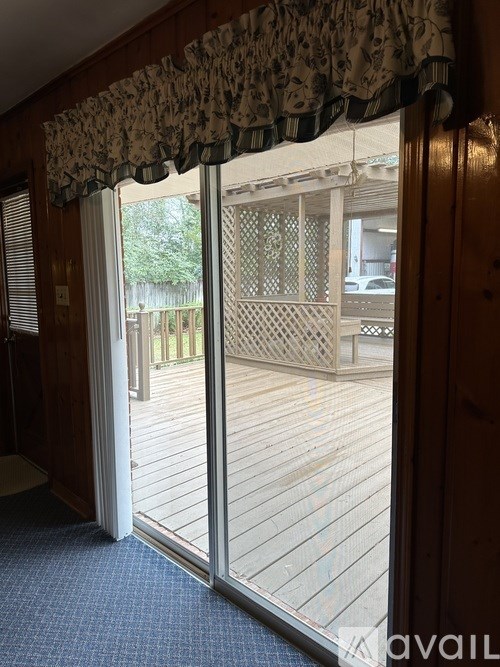 A room with a view of a deck through a sliding glass door.