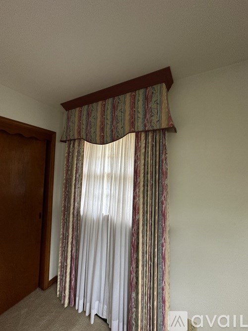 A room with a window covered by a striped curtain.