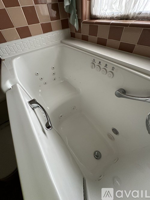 A white bathtub with a silver faucet and a window above it.