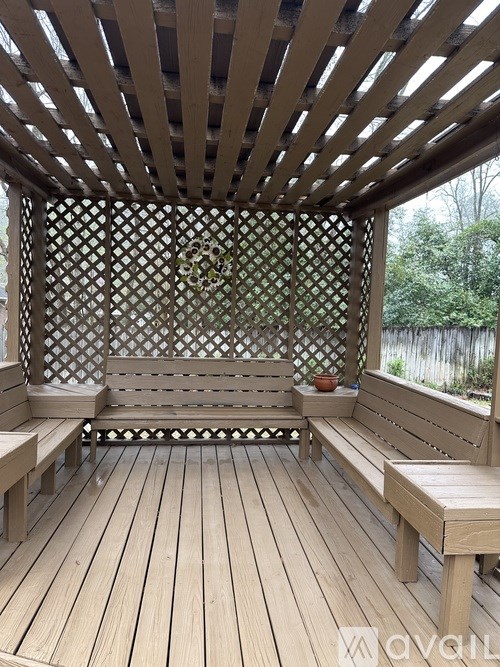 A wooden pergola with a lattice top and benches.