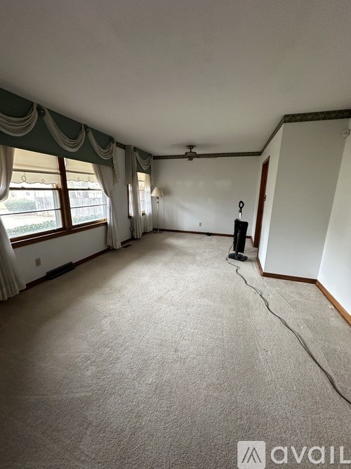 A room with a carpeted floor and a window with curtains.