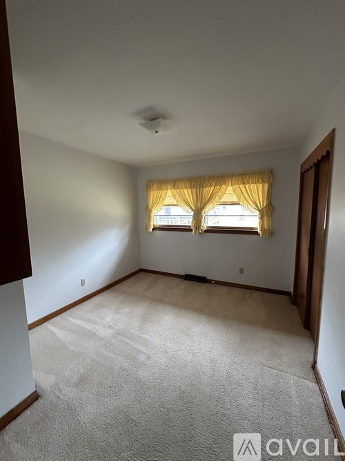 A room with a window covered by yellow curtains.