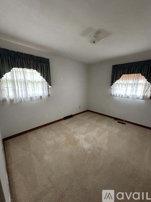A room with two windows and a carpeted floor.