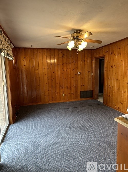 A room with wooden walls and a ceiling fan.