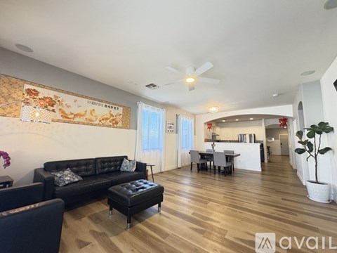 A living room with a black couch and a wooden floor.