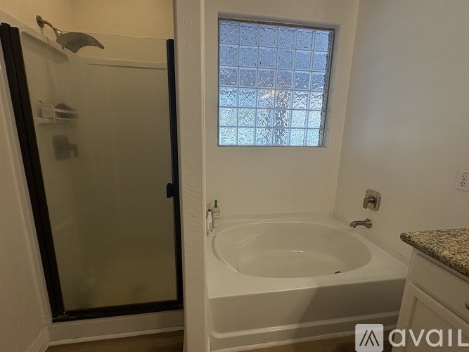 A bathroom with a white tub and a glass shower door.