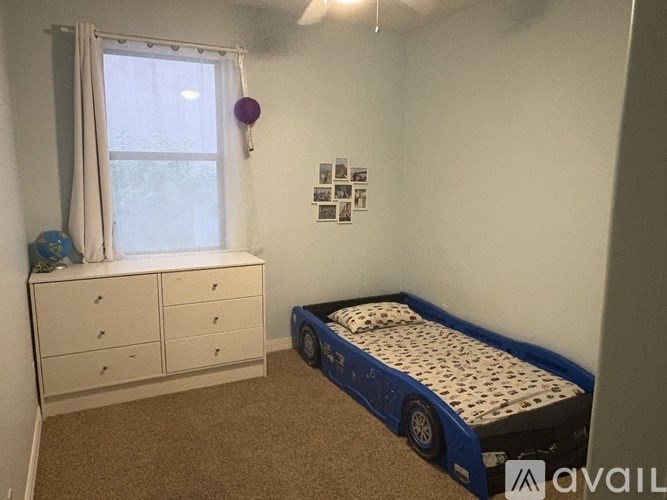 A bedroom with a bed, dresser, and window.