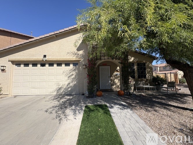 A house with a white garage door and a tree in front.