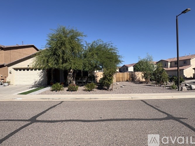 A street view with a house and a tree in the foreground.