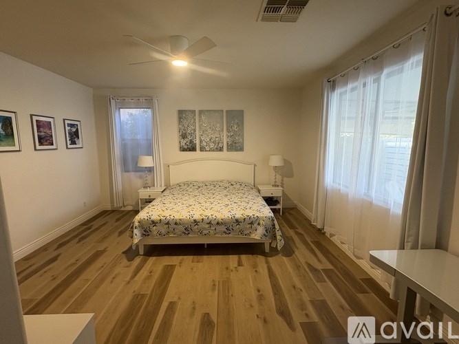 A bedroom with a bed, a ceiling fan, and a window with curtains.