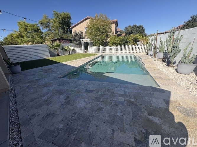 A backyard with a pool and a white picket fence.
