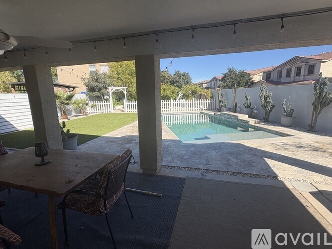 A patio with a table and chairs overlooking a pool.
