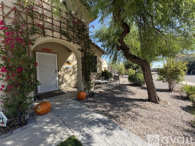 A white door is flanked by pumpkins and a tree.