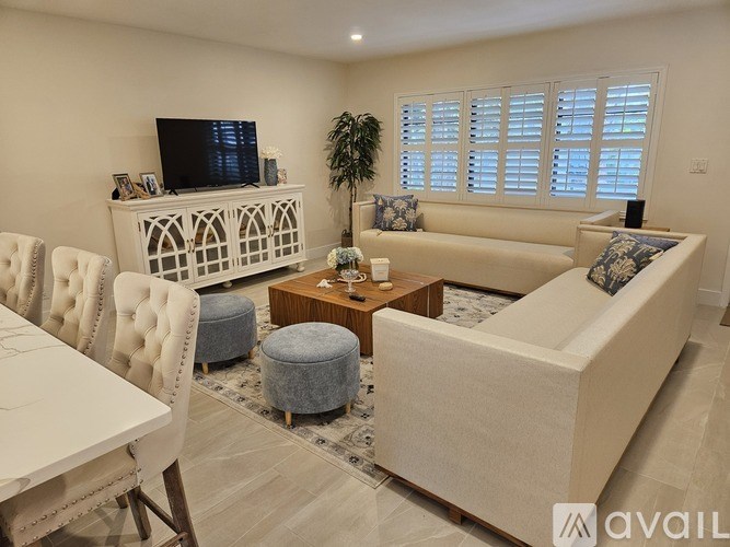 A living room with a white sofa, a white table, and a TV on a white cabinet.