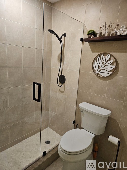 A white toilet in a tiled bathroom with a shelf above it.