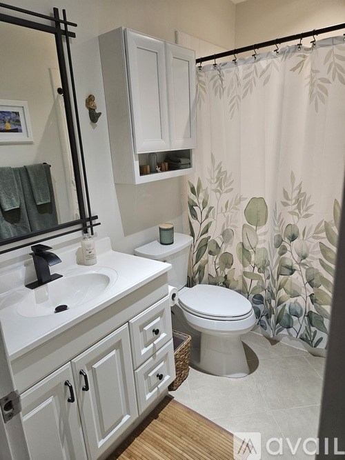 A bathroom with a toilet, sink, and shower curtain.