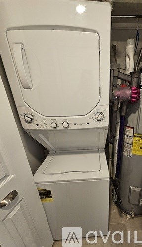 A white dryer is in a cluttered room.