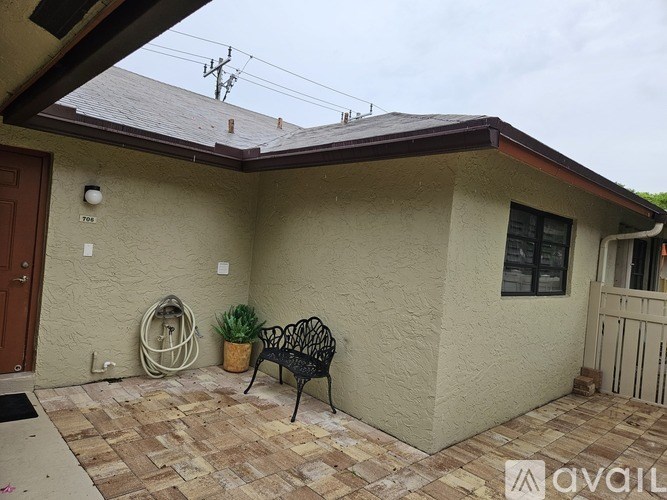 A house with a brown door and a black metal bench.