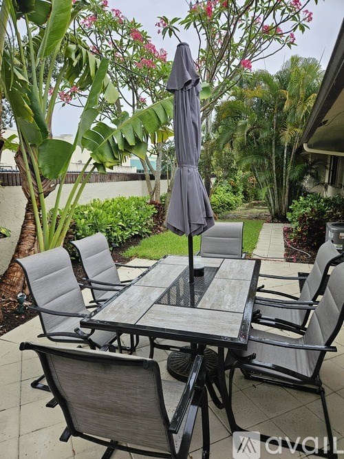 A grey umbrella is on a table with chairs around it.